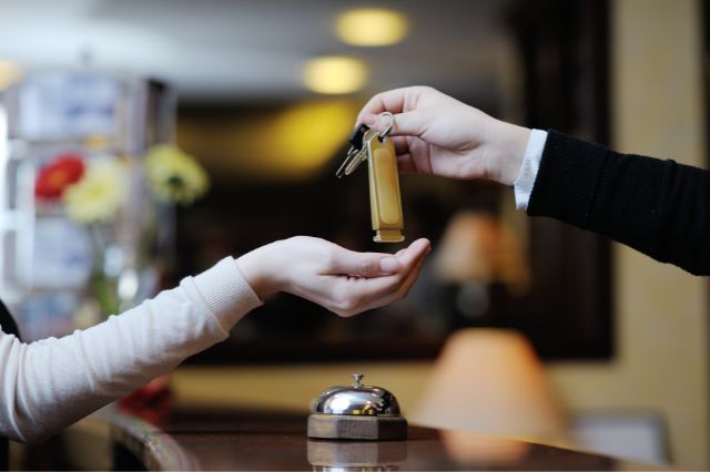 海外のホテルでコンセントについて英語で質問しながら鍵を受け取る人