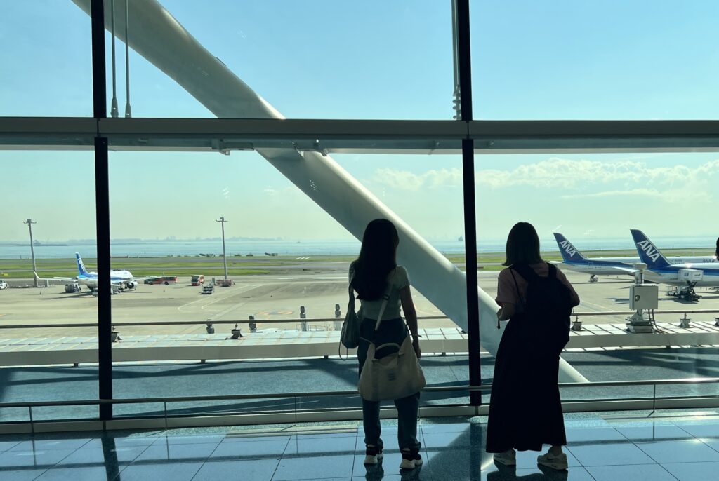 羽田空港出発の女子旅で荷物を抱えて乗り込む飛行機を眺める2人