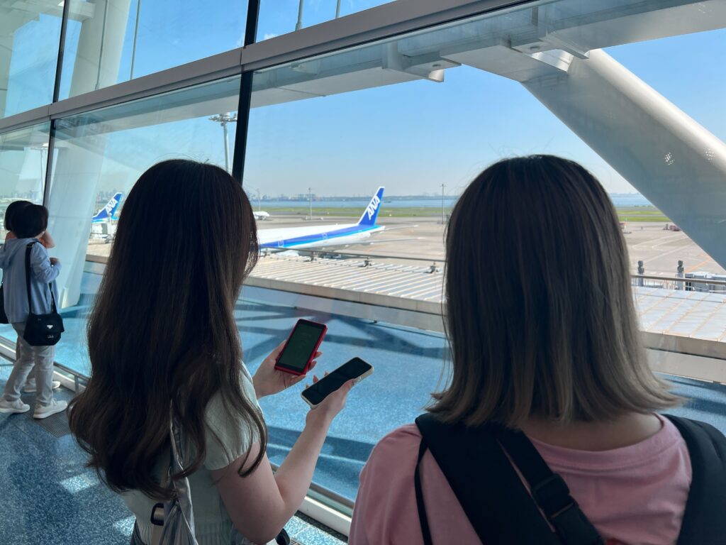 羽田空港第2ターミナル出発ゲートで乗り込む飛行機を眺める2人（女子旅にてWiFi端末を準備した筆者）